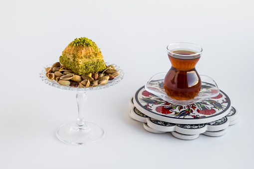 Close-up taken of Traditional Turkish Tea and a slice pistachio dry baklava on white with copy space.The Sugar Feast concept.