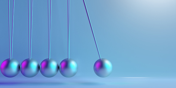 Newton's Cradle with metal balls hanging in a line with the released ball concept of cause and effect, action and reaction, balance and imbalance. Beautiful pendulum silver metallic spheres on coloured background with drop shadow and large copy space.