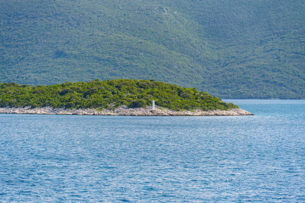 A small rectangular island sits in the middle of a vast lake, surrounded by water and grassy landscapes. The horizon is dotted with coastal and oceanic landforms, creating a serene natural landscape