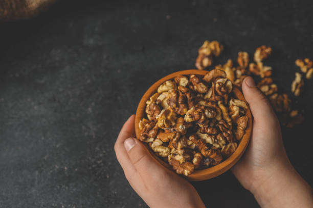 istock Walnuts in a plate in hands on a dark background 2148448223