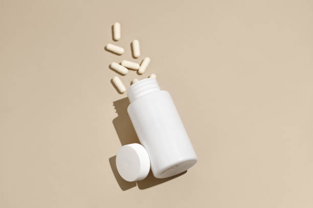 istock White mockup jar with scattered pills capsules at an angle on a beige isolated background. Concept of pharmacy, health, medical and dietary supplements. Image for your design 2148448865
