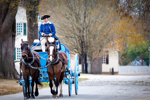 Williamsburg, Virginia, USA - March 21, 2024: A horse-drawn carriage travels the streets of Colonial Williamsburg.