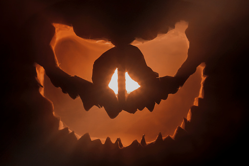 Halloween pumpkin head jack lantern and candles on black background.