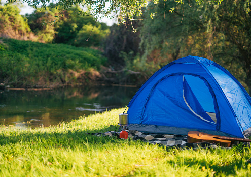 Picture of a tent in nature on a lawn next to a river.