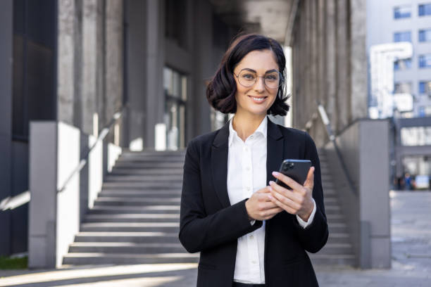 istock Professional businesswoman using smartphone outdoors in modern urban setting 2148451136