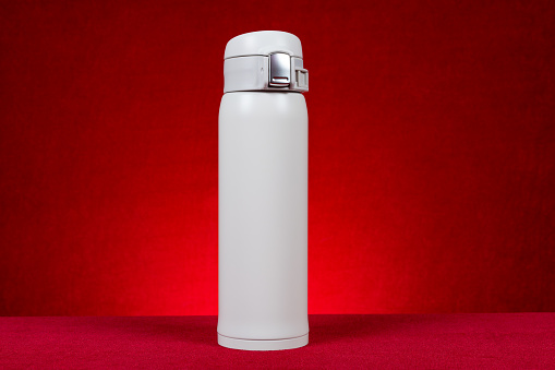 a white vacuum tumbler at horizontal composition on red