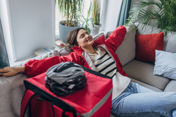 istock Content young woman relaxing on couch with delivery bag 2148451817