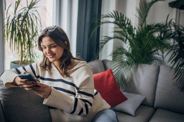 istock Young woman relaxing with smartphone on couch 2148452042