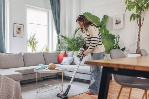 istock Young woman vacuuming living room 2148452722