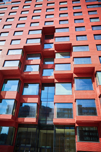 Part of a new multi-story red office building under construction from below. Full frame