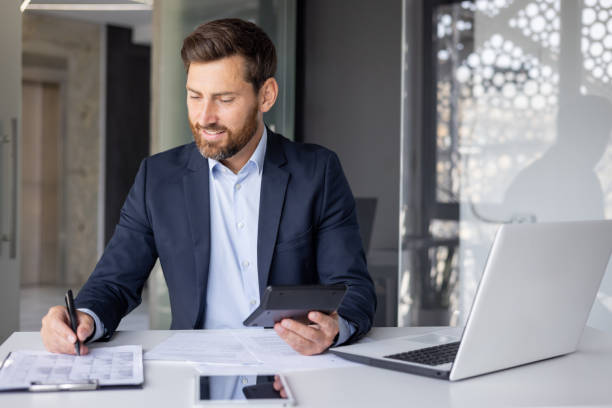 istock Smiling businessman completing paperwork in office 2148453257