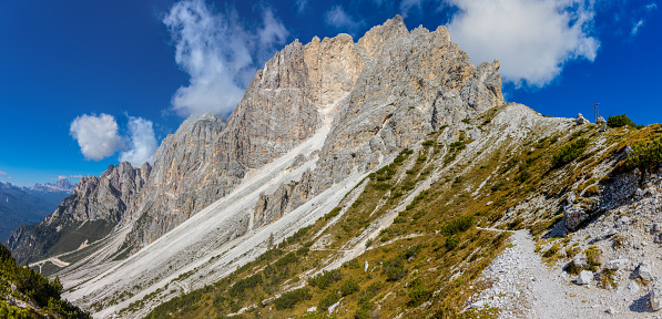 Wide panorama landscape of Dolomites mountains, Alpi Dolomiti beautiful scenic landscape in summer. Italian Alps mountain summits and rocky peaks above green valley alpine panoramic scene