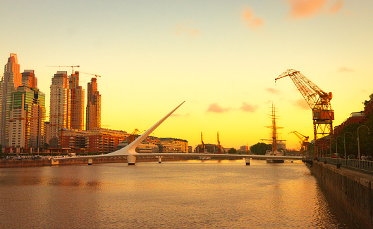 Buenos Aires, Argentina. March 24, 2009. 
At sunset, the Puente de la Mujer, located in the affluent neighborhood of Puerto Madero, gracefully spans the Rio de la Plata, symbolizing Argentina's modernity and prosperity. The bridge harmonizes with the orange horizon of a beautiful sunset, encapsulating the dynamic spirit and architectural elegance of the country.