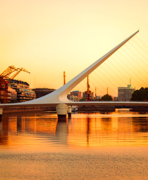 Captivating Sunset at Puente de la Mujer in Puerto Madero Buenos Aires, Argentina. March 24, 2009. 
At sunset, the Puente de la Mujer, located in the affluent neighborhood of Puerto Madero, gracefully spans the Rio de la Plata, symbolizing Argentina's modernity and prosperity. The bridge harmonizes with the orange horizon of a beautiful sunset, encapsulating the dynamic spirit and architectural elegance of the country. puente de la mujer stock pictures, royalty-free photos & images
