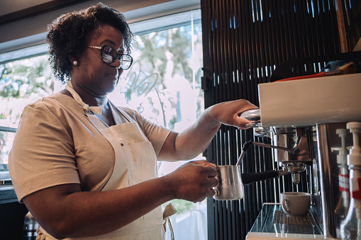 Senior woman preparing coffee for customers