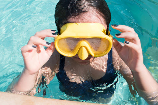 High angle view of girl taking googles out in swimming pool in hot sunny day