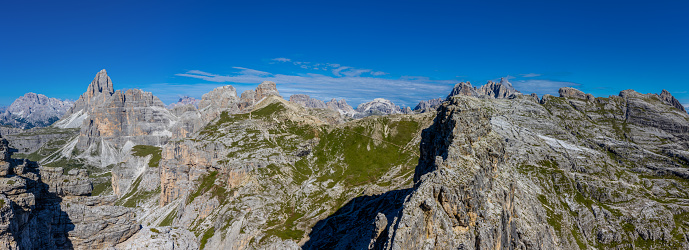 Wide panorama landscape of Dolomites mountains, Alpi Dolomiti beautiful scenic landscape in summer. Italian Alps mountain summits and rocky peaks above green valley alpine panoramic scene