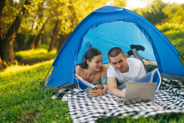 istock Happy couple using laptop computer while relaxing in camping tent in nature. 2148454929