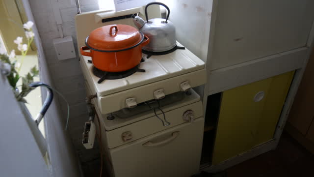 Vintage kitchen stove with an orange pot and kettle, showcasing retro cooking appliances. Perfect for themes of domestic life and culinary history