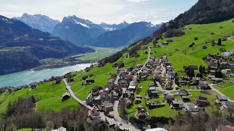 Swiss town located on green mountain with Lake Walen in the valley. Aerial forward wide shot. Amden, Switzerland.