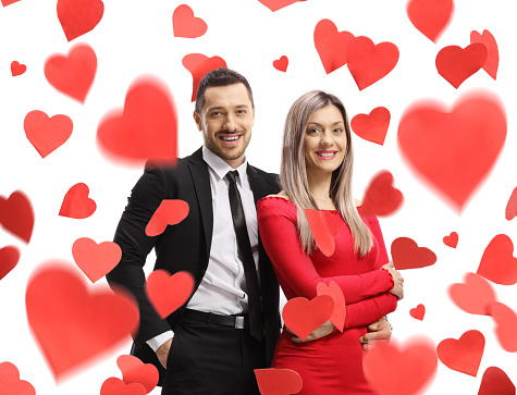 Man and a beautiful woman posing in embrace under red hearts isolated on white background