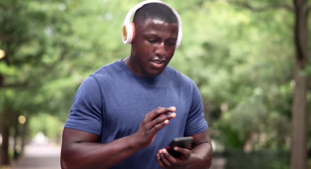 Headphones, black man and cellphone on run for music, fitness and wellness outdoor for workout. Male person, runner and athlete strong for exercise, health or training for cardio with mobile