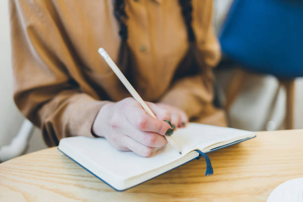 istock A woman is writing in a notebook with a pencil 2148460759