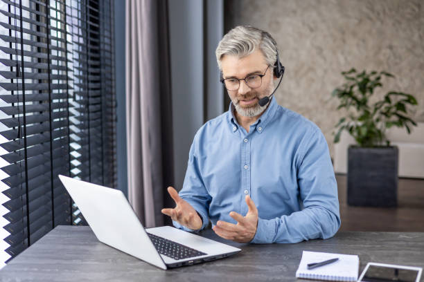 istock Professional mature man with headset in video call on laptop, remote work concept in modern home office 2148462873