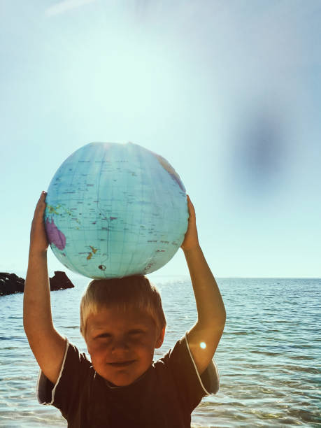 istock Child Plays with Globe Ball by Sea 2148464244