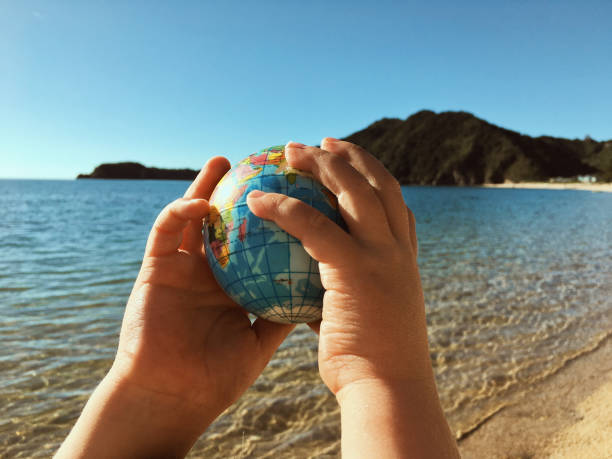 istock Child Plays with Globe Ball by Sea 2148464245