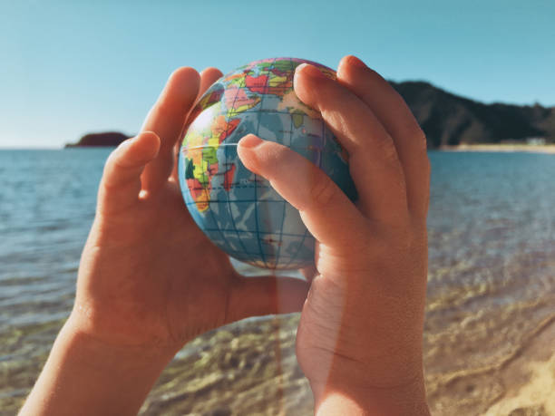 istock Child Plays with Globe Ball by Sea 2148464247