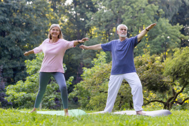 istock Senior couple practicing yoga together in a serene park setting 2148465083