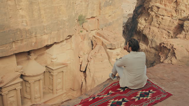 Tourist sitting on a red carpet overlooking Petra