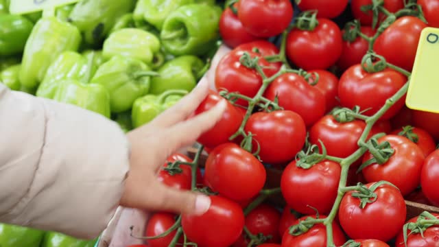 women Choose ripe tomato in market
