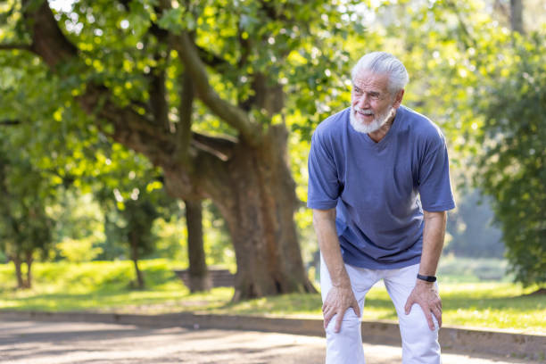 istock Tired senior gray-haired man is standing bent over in the park and resting after an active walk, run and workout 2148467579