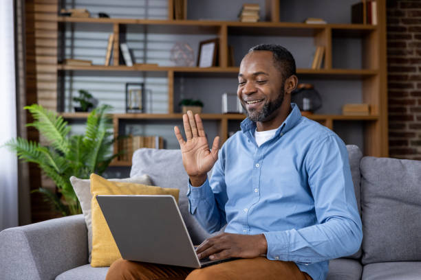 istock Smiling african american man video calling using laptop at home 2148468454