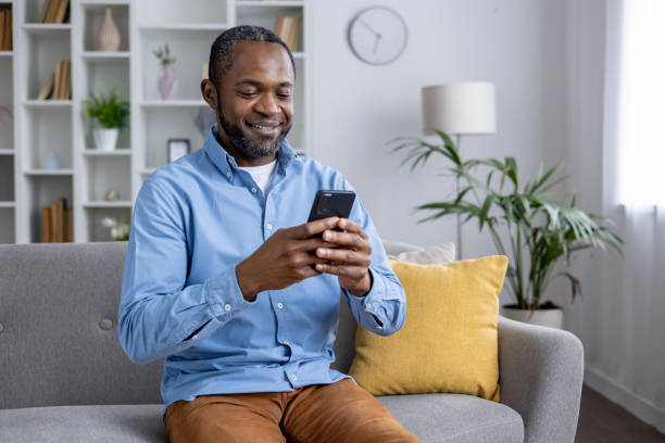 istock Casual man using smartphone on couch at home 2148469226