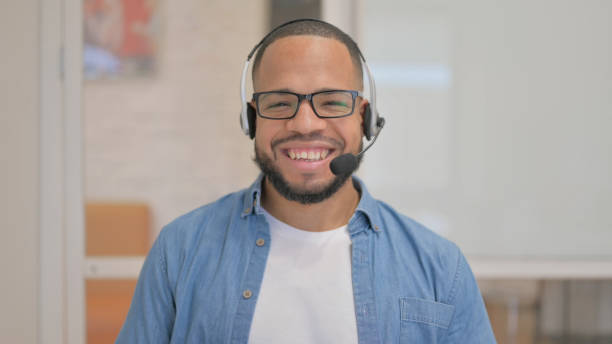 istock Smiling African Man with Headset Looking at Camera in Call Center 2148469895