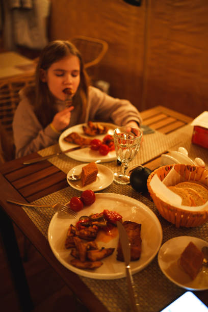Selective focus. Teenage girl eating in the semi-darkness in a cafe.