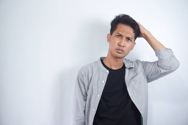 istock Young man with shirt having doubts and with confuse face expression while scratching head on isolated white background 2148470693