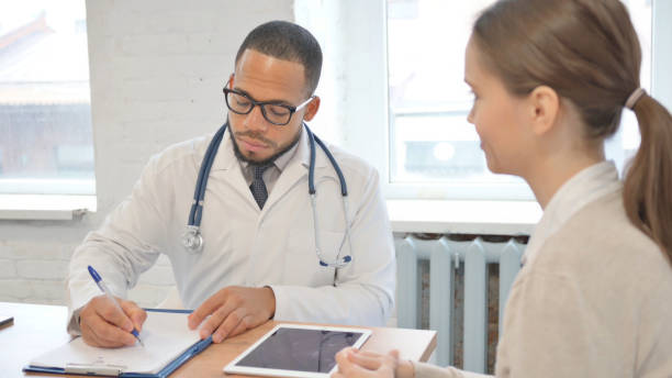 istock African Doctor Writing Medical Report while Talking with Senior Patient 2148470963