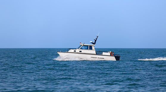 A white Coast Guard boat sailing along the coastline