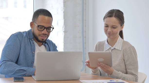 istock Multi Ethnic Casual People Discussing Project on Laptop and Tablet 2148471380