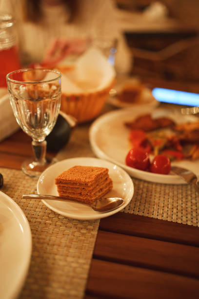 A slice of honey cake on a plate. Selective focus. on a wooden table in the semi-darkness