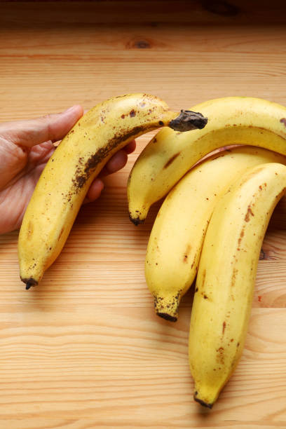 istock Hand holding a ripe banana with brown spots on its peels 2148472639