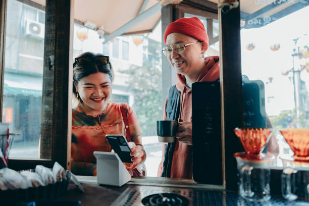 a woman uses her smartphone to make a payment with the cashier. She scans the QR code using a card reader to complete a convenient contactless payment.