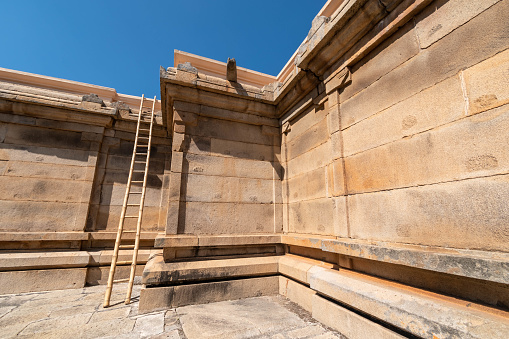 Stone architecture with a wooden ladder at Shravanabelagola, signaling historical cultural heritage.