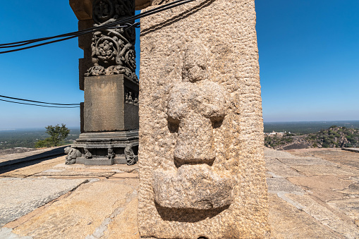 Stone carving on the summit of Shravanabelagola with a vast landscape in the background.