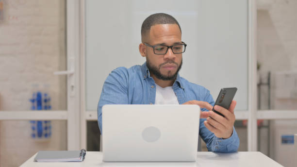 istock Mixed Race Man Working on Laptop and Using Smartphone 2148473820