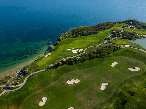 An overhead perspective of a golf course situated near the ocean, showcasing the green fairways and blue waters.